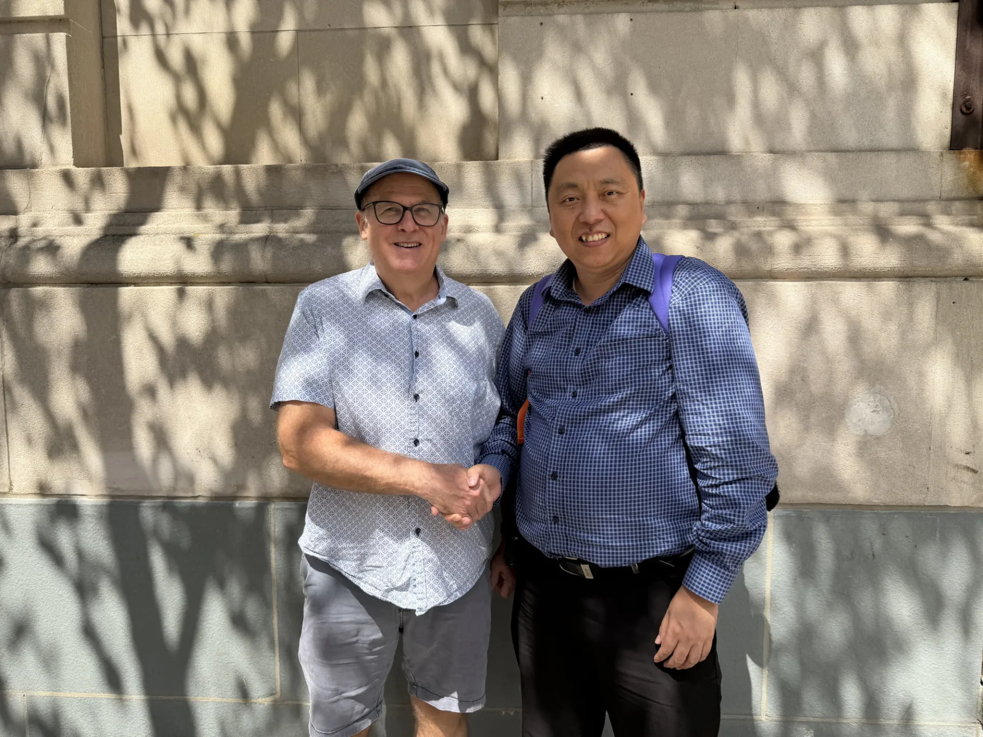 Dr. Qi Duan shaking hands with Dr. Andrew Laine.